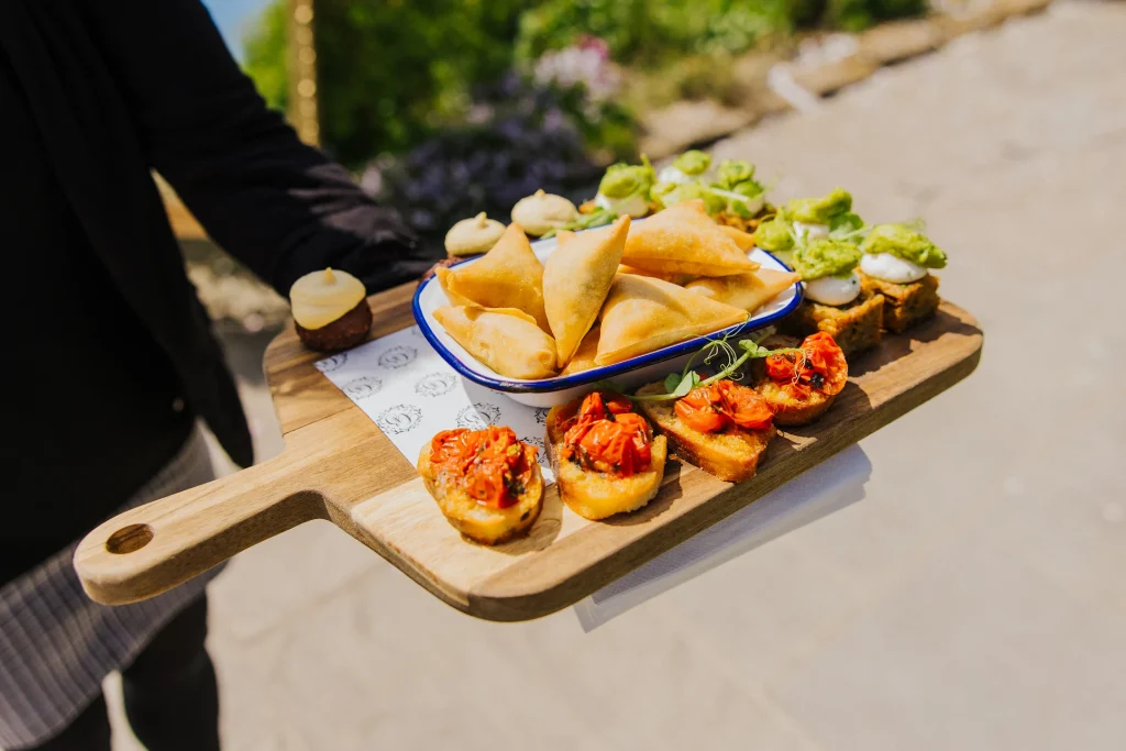 canapes on a wooden board, held by a waitress