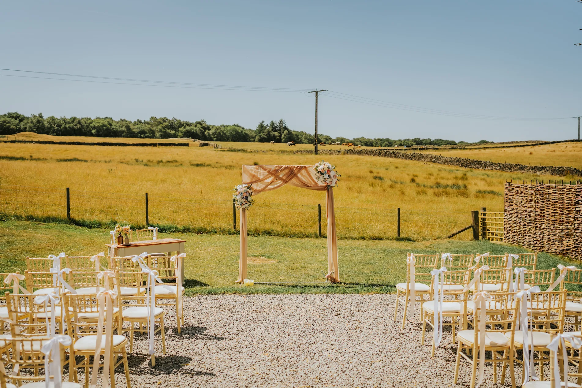 outdoor wedding ceremony with chairs laid out in front of a sunny field